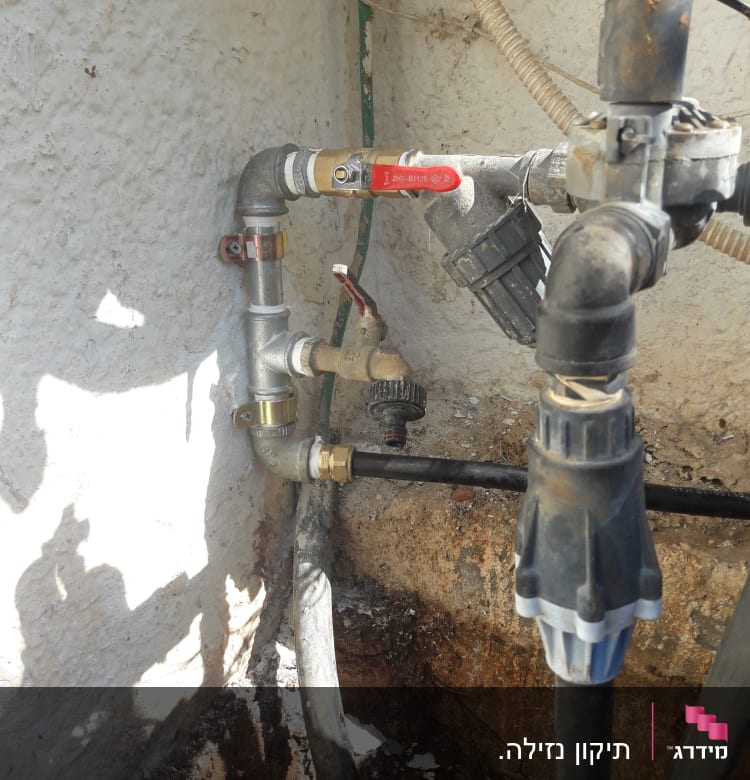 צינורות מים עם ברזים ומחברים על קיר חיצוני